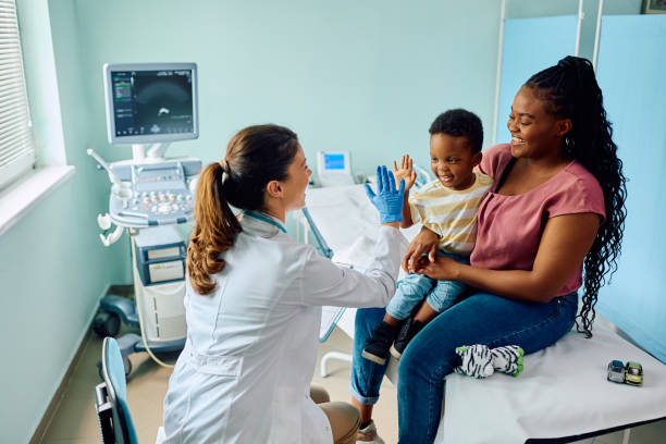 Happy African American boy giving high five to his pediatrician after medical examination at doctor's office.